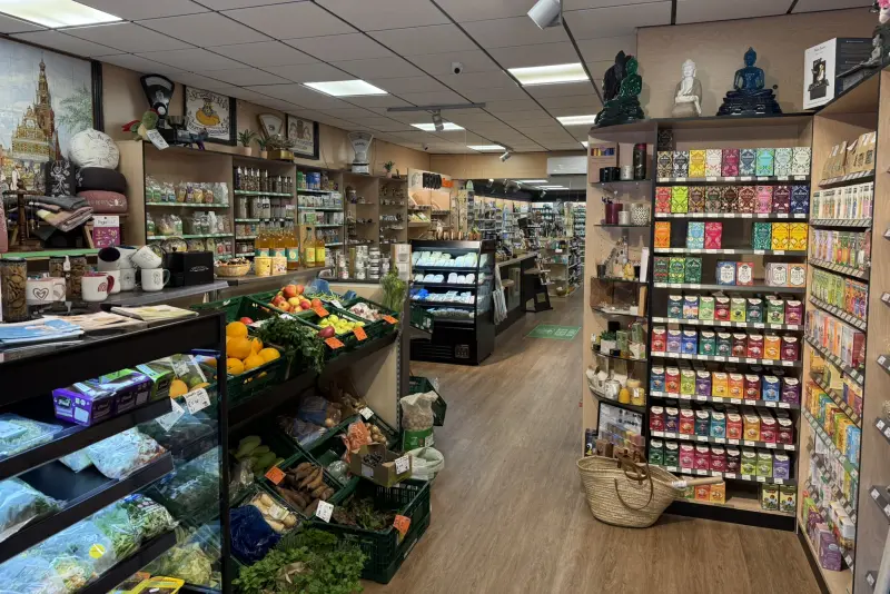 Het interieur van de winkel: kratten met groente en fruit, schappen vol thee en op de wand een tegeltableau
