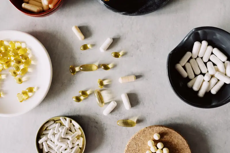 Schaaltjes met capsules en supplementen op een lichte ondergrond