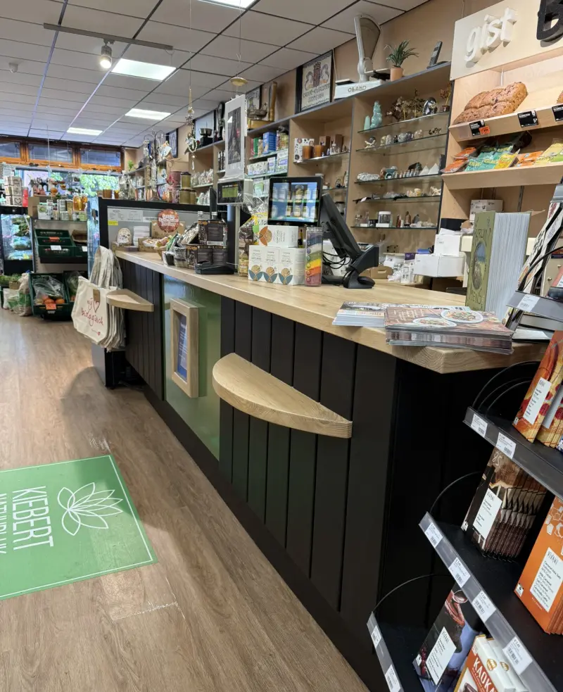 De toonbank van de winkel met op de vloer een groene mat met het logo van Kiebert Natuurlijk